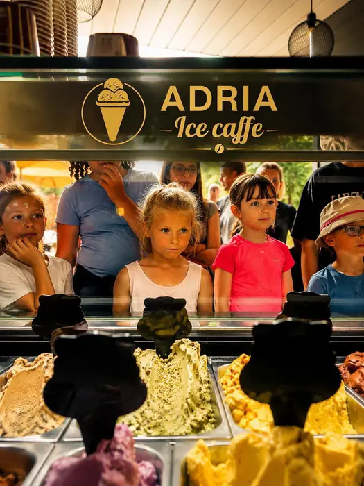 Deti pri vitríne Adria Ice Caffe si vyberajú kopčekovú zmrzlinu
